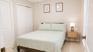Een slaapkamer met een bed, een nachtkastje, een plafondventilator en twee ingelijste foto's aan de muur.