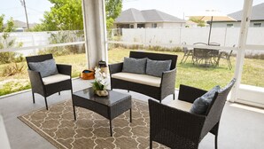 Een terras met rieten meubels, een bijzettafeltje en een decoratieve vaas.