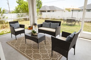 Eine Terrasse mit Korbmöbeln, einem Couchtisch und einer dekorativen Vase.