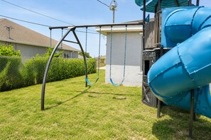 Ein Spielplatz mit Schaukeln und einer Rutsche.