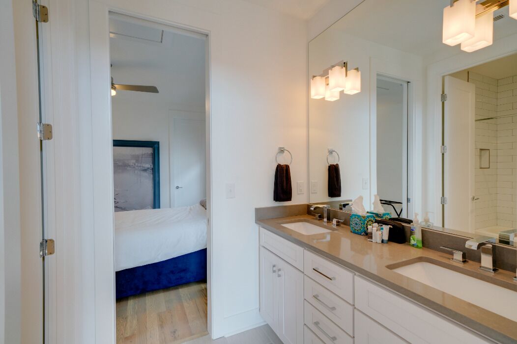 A modern bathroom with a large mirror, two sinks, and a shower area.