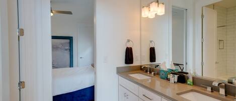 A modern bathroom with a large mirror, two sinks, and a shower area.
