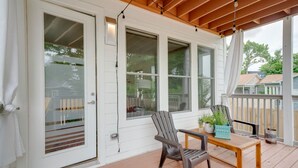 Eine überdachte Veranda mit einem Holztisch, zwei Stühlen und einem Blumentopf.