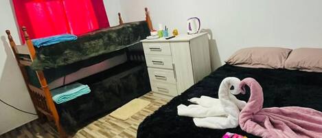 A bedroom with a bed, a desk, a chair, a wardrobe, and a red curtain.