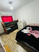 Un dormitorio con cama, escritorio, silla, armario y una cortina roja.