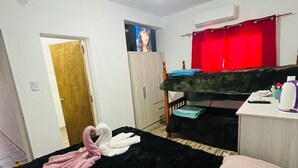 Une chambre à coucher avec un lit, un bureau, une chaise, une armoire et un rideau rouge.
