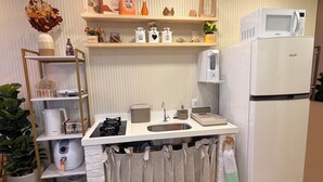 A compact kitchen with a built-in microwave, a refrigerator, a sink, and a shelf with decorative items. - Paradise in Praça 19: 3 min from the village and 5 min from the natural pools! (Ipojuca)