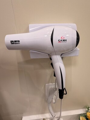 A white spa dryer with the brand GAMA, labeled as a professional Italian model, mounted on a wall with a power outlet below it. - Paradise in Praça 19: 3 min from the village and 5 min from the natural pools! (Ipojuca)