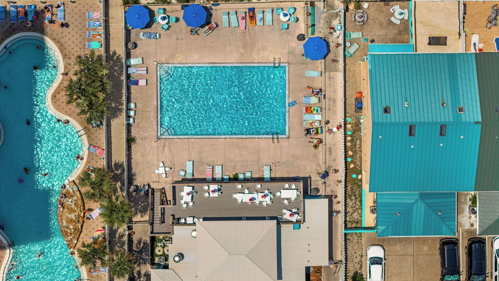Ein Poolbereich auf dem Dach mit mehreren Liegestühlen und Sonnenschirmen, einem Schwimmbecken und einer überdachten Sitzgelegenheit.