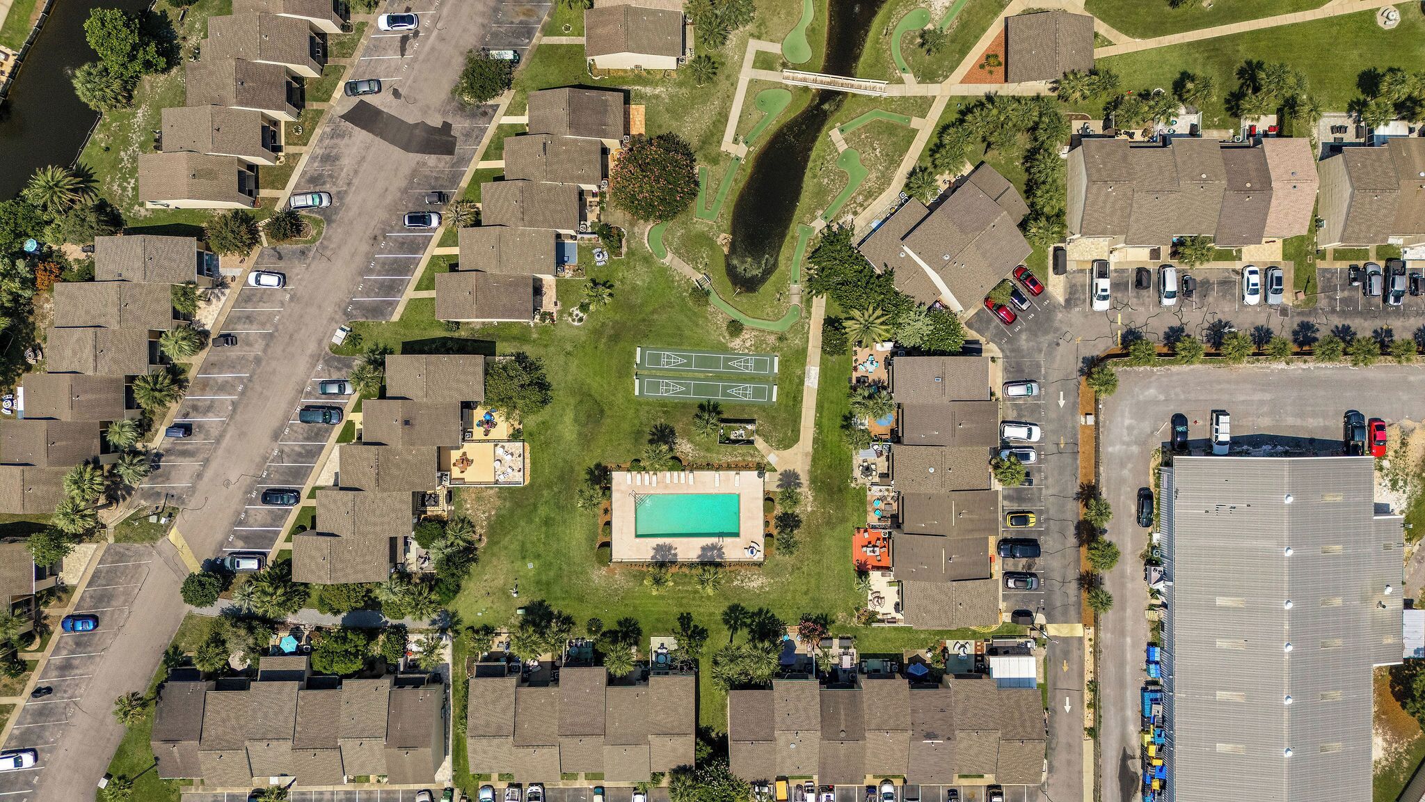 An aerial view of a residential area with multiple houses, a swimming pool, and a tennis court.