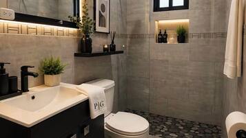 Une salle de bain moderne avec un grand miroir, des toilettes, un lavabo et un espace douche.