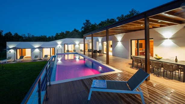 A modern outdoor pool area with a wooden deck, lounge chairs, and a dining area with a table and chairs. - Luxurious Villa Istria Green with private pool - for families and nature lovers (Boljevići)