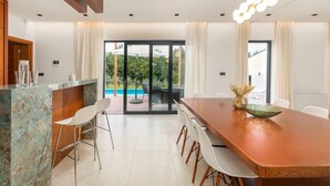 A modern dining area with a wooden table, white chairs, and a glass-top island. - Luxurious Villa Istria Green with private pool - for families and nature lovers (Boljevići)