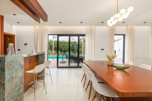 Ein moderner Essbereich mit Holztisch, weißen Stühlen und einer Insel mit Glasplatte.