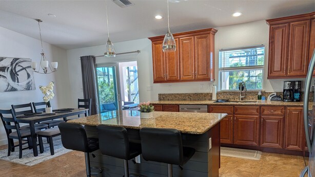 Una cocina moderna con encimeras de granito, armarios de madera y una isla central con taburetes de bar.