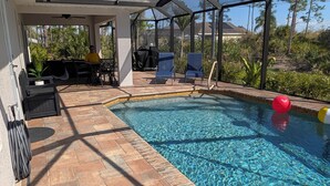Una piscina cubierta al aire libre con un patio, que incluye asientos y una parrilla.