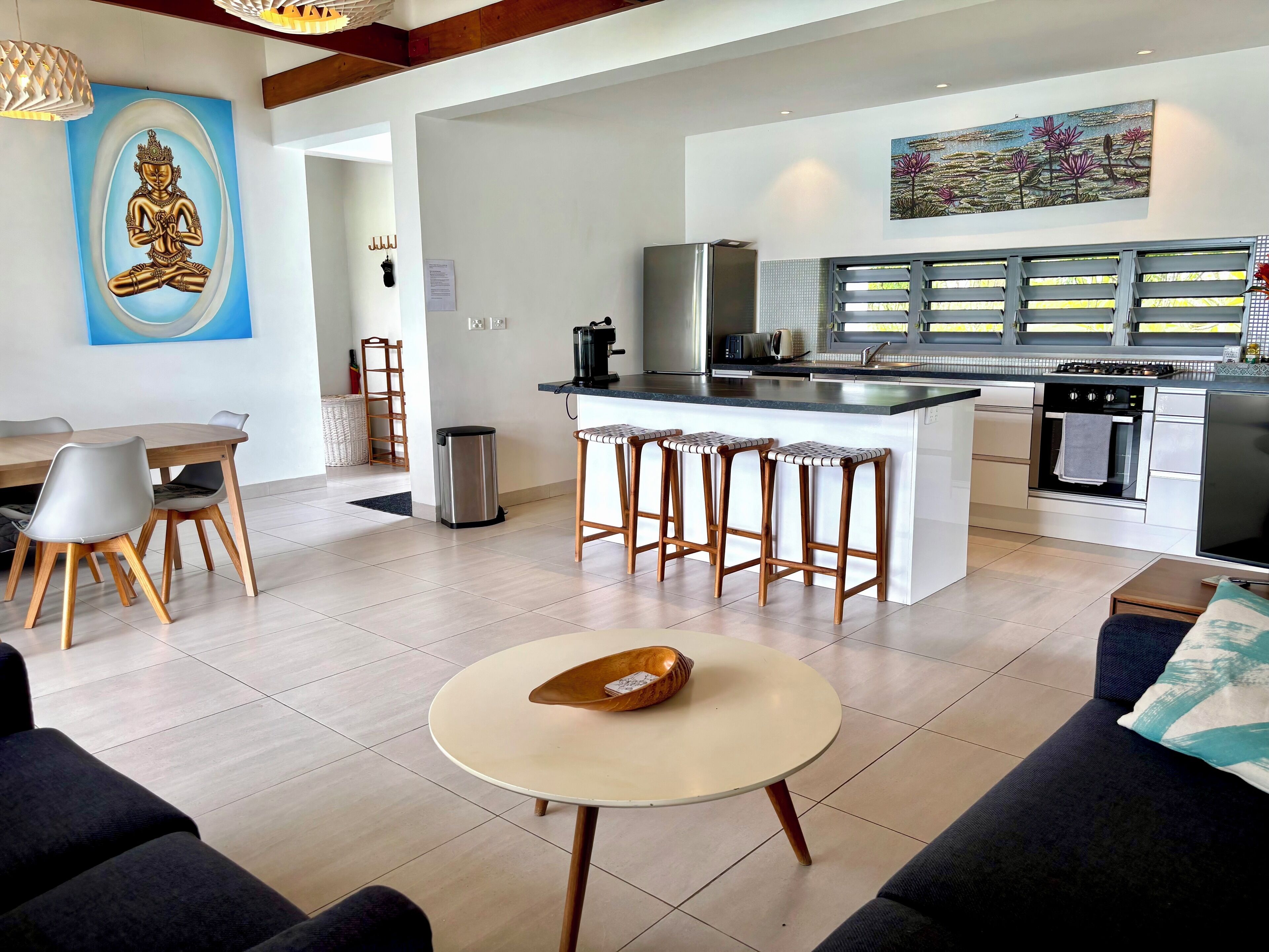 Une cuisine moderne dotée d’un îlot central, de tabourets de bar et d’un coin repas avec une table ronde.