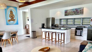 A modern kitchen with a central island, bar stools, and a dining area with a round table.