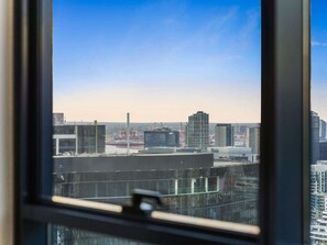 Une vue sur la ville à travers une fenêtre, avec des bâtiments et des grues de construction en arrière-plan.