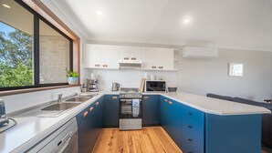 Eine moderne Küche mit Geschirrspüler, Backofen, Mikrowelle und einem großen Fenster.