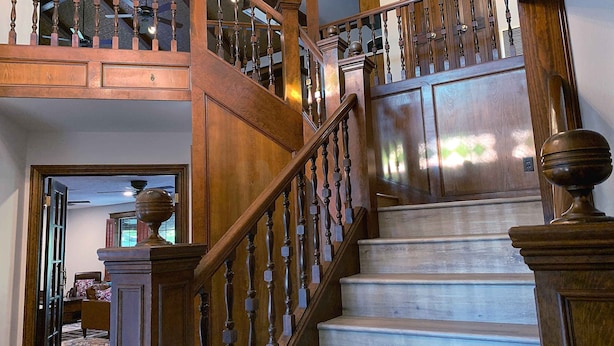 A wooden staircase with a balustrade, leading to a landing with a door.