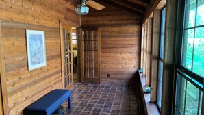 A wooden interior with a bench, a ceiling fan, and a large window.