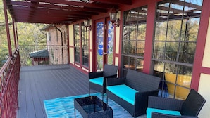 A covered outdoor seating area with wicker furniture and a blue patterned rug.