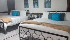 A hotel room with two beds, a ceiling fan, and artwork on the walls.