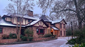 A traditional brick house with a steeply pitched roof, a chimney, and a well-maintained garden.