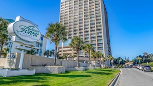 A tall hotel building with a sign reading 'Ocean Forest Plaza' and a parking area with cars. - Ocean Forest Plaza 2108 (Myrtle Beach)