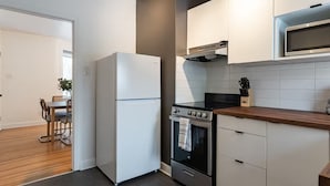 A modern kitchen with white cabinetry, a built-in oven, and a microwave. - Home-Style 1BR Near HSC | Free Parking (Winnipeg)