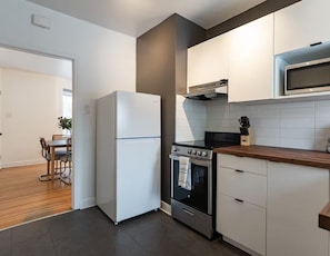 Una cocina moderna con refrigerador, estufa, microondas y encimera de madera.