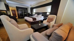 A hotel room with a bed, two armchairs, a sofa, a coffee table, and a TV. - Le Numidien - Aeroport (Algiers)