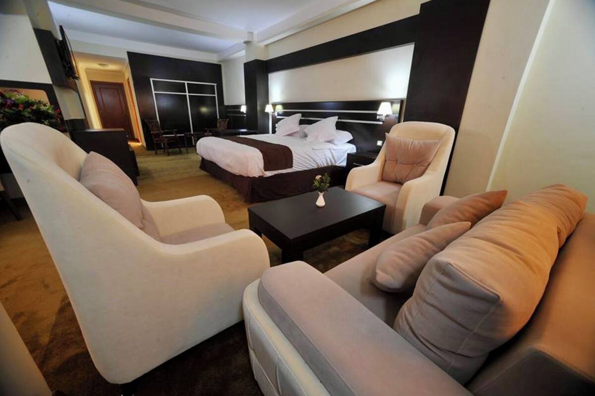 A hotel room with a bed, two armchairs, a sofa, a coffee table, and a TV.