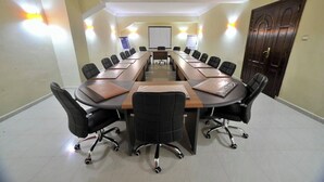 A conference room with a long table, black chairs, and a whiteboard at the front. - Le Numidien - Aeroport (Algiers)