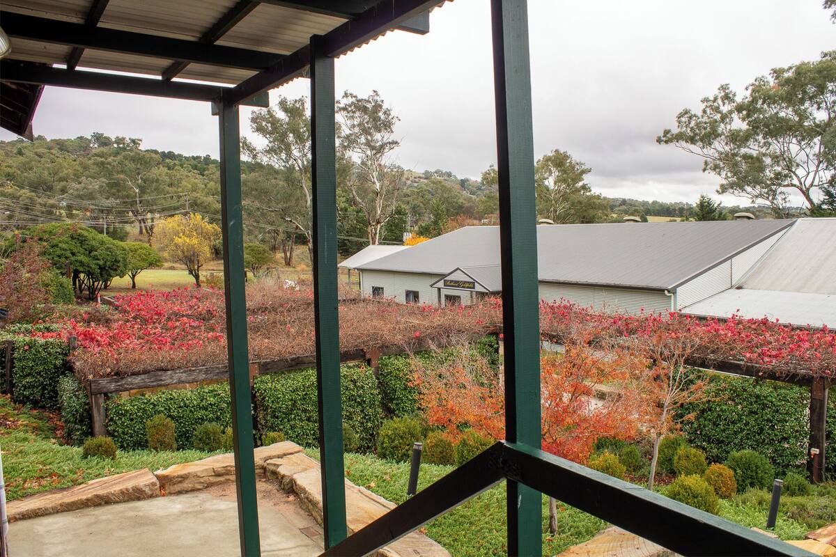 A covered outdoor area with a view of a house and surrounding garden.