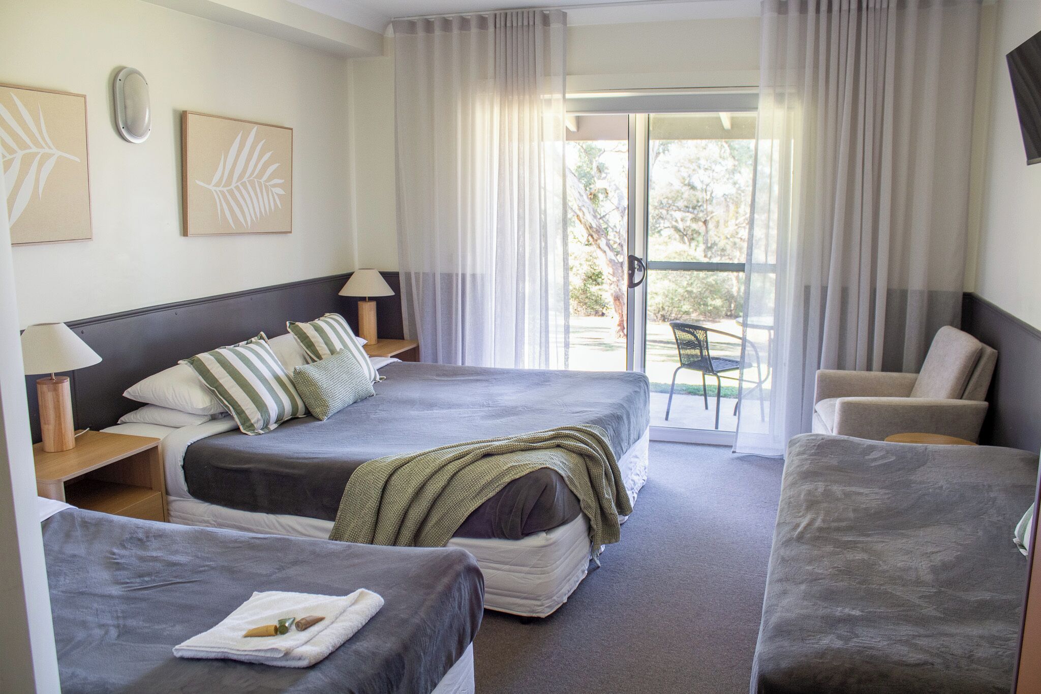 Habitación de hotel con dos camas, un sofá, una silla y un balcón con vistas.