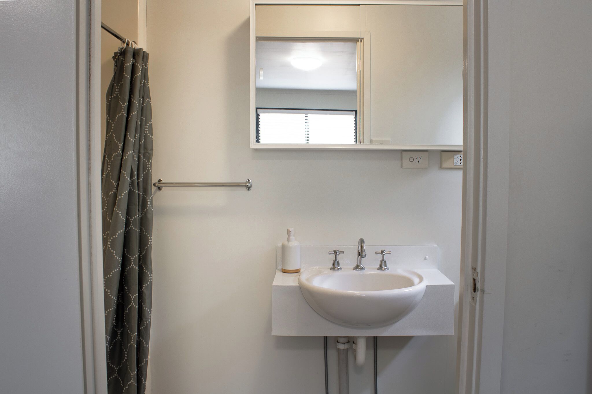 A bathroom with a white sink, a mirror, and a shower curtain.