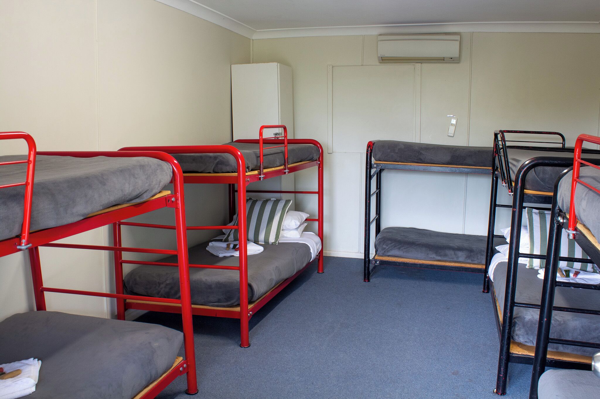 Bunk beds with grey bedding, a white wall, and a small white cabinet.