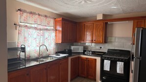 A kitchen with wooden cabinets, a black stove, a microwave, and a refrigerator.