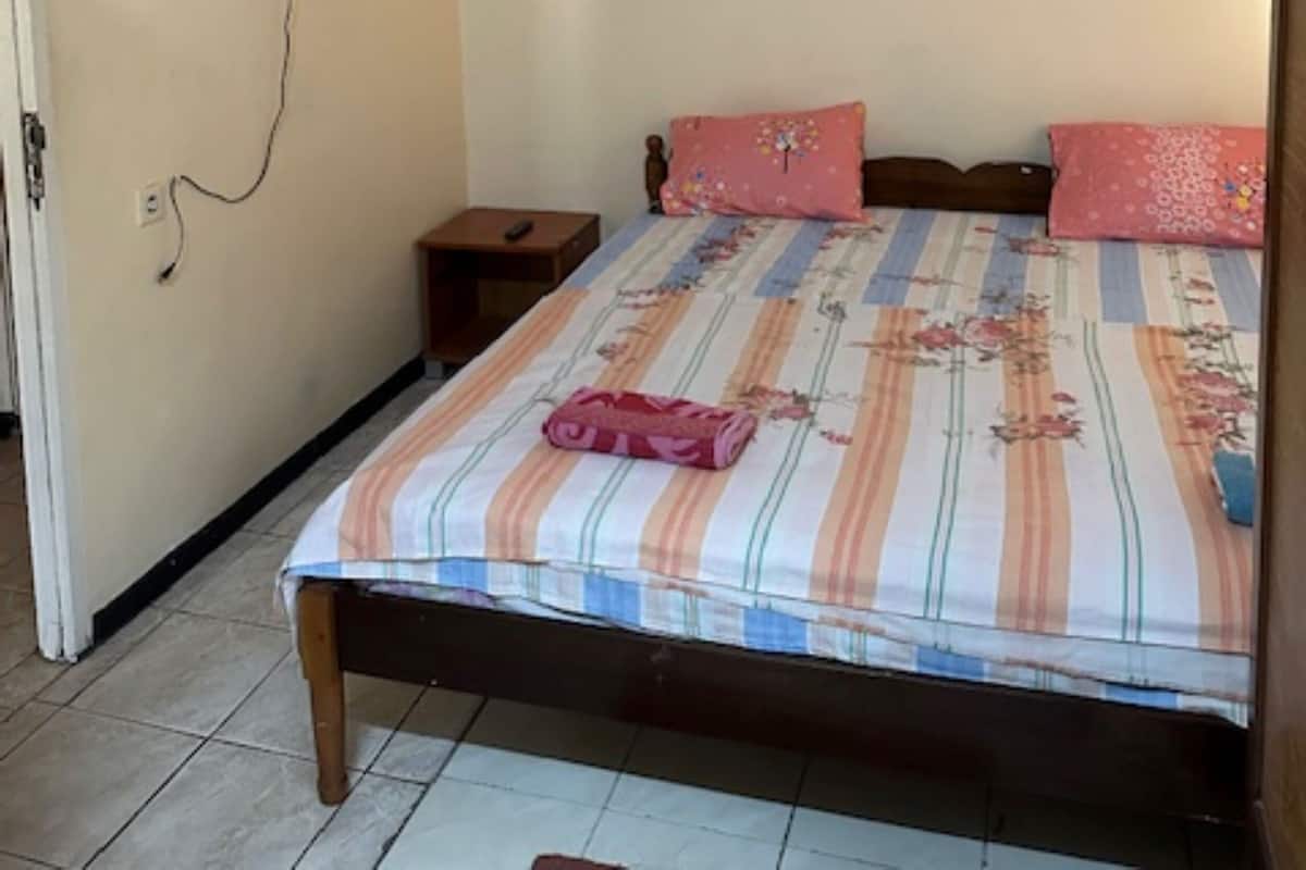 A bedroom with a bed, a TV mounted on the wall, and an air conditioning unit.