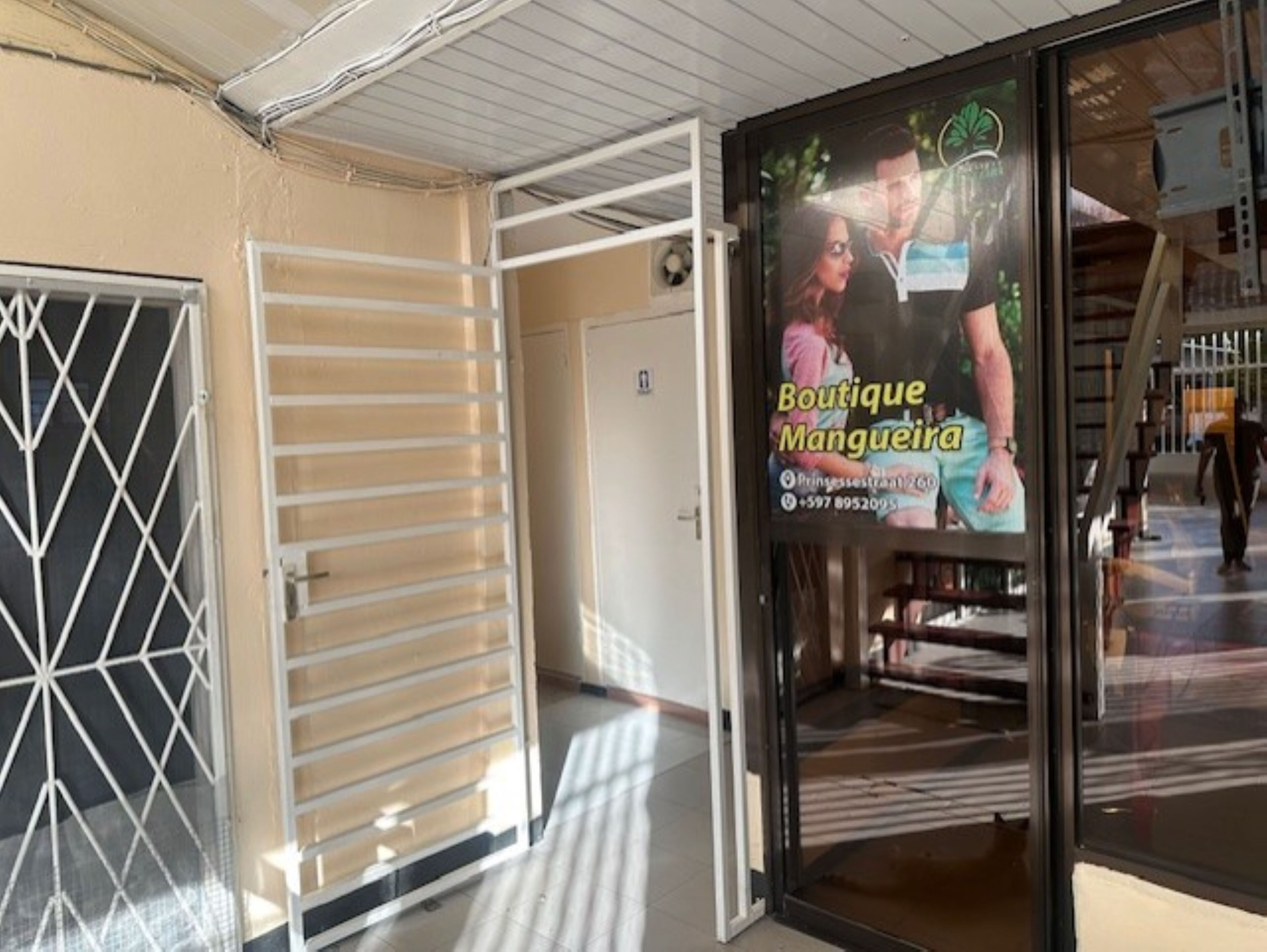Fachada con puerta de cristal, persiana metálica y un letrero que anuncia una boutique.