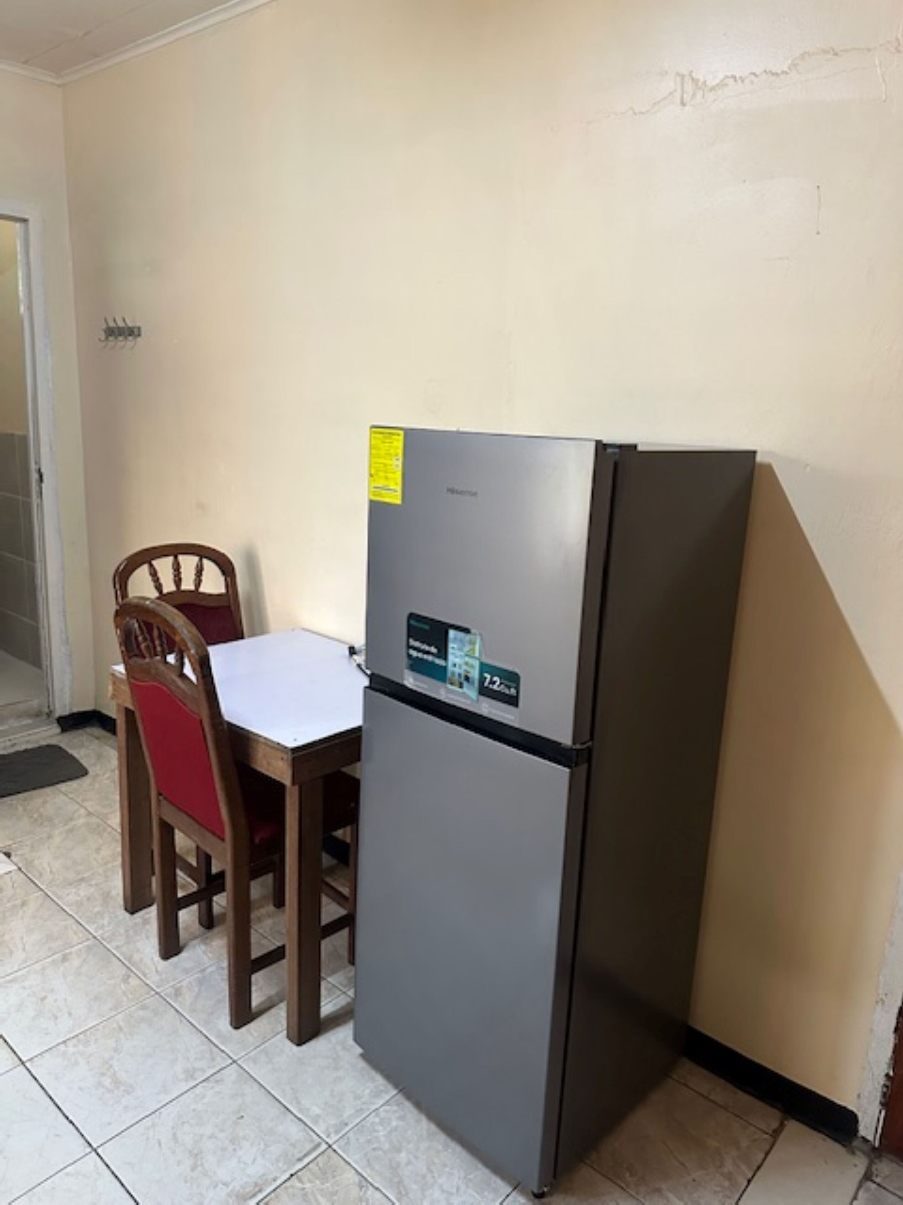 A compact kitchen with a refrigerator, a dining table, and two chairs.