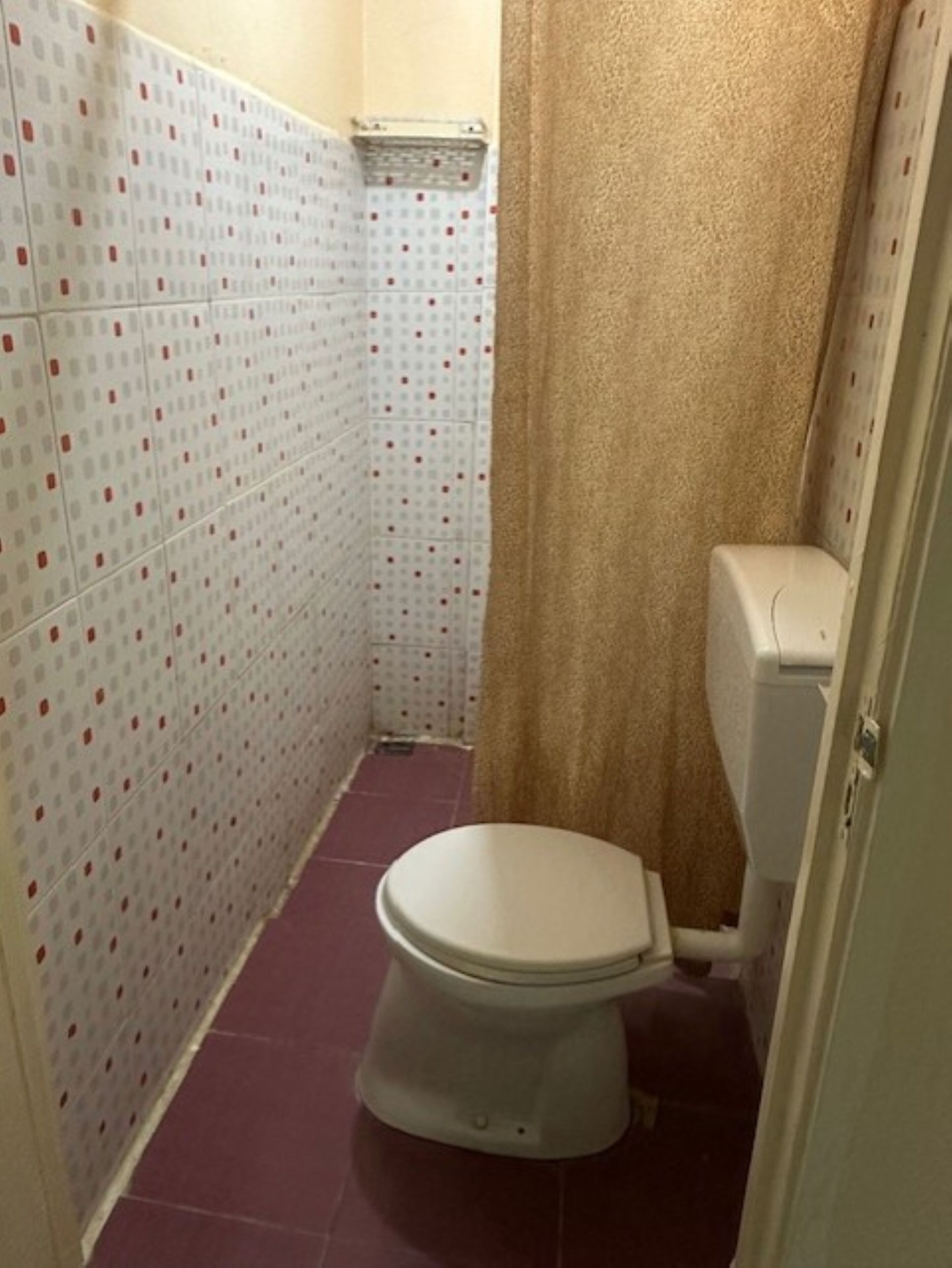 Um banheiro pequeno com vaso sanitário, chuveiro cortinado e paredes azulejadas.