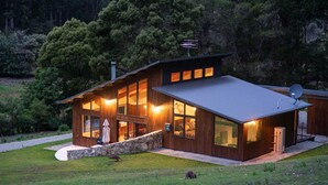 A modern house with large windows, a stone pathway, and a satellite dish. - Bruny Island Haven - The Studio (Adventure Bay)