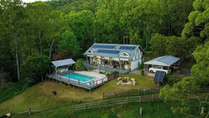 Een modern huis met een zwembad, zonnepanelen en een omheinde tuin.