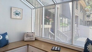 Una habitación con ventanal, un cuadro enmarcado, un cartel que dice 'Beach Towns' y una pequeña mesa con adornos.