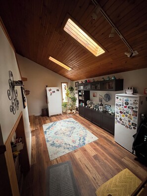 A kitchen with wooden flooring, a central island, and a refrigerator with magnets. - Home available for EAA July 17-25,2026 (Oshkosh)