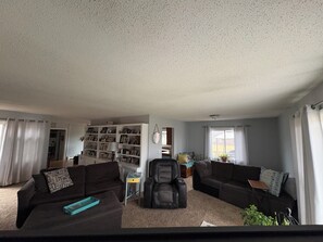 A living room with two dark sofas, a bookshelf, a chair, and a small table. - Home available for EAA July 17-25,2026 (Oshkosh)