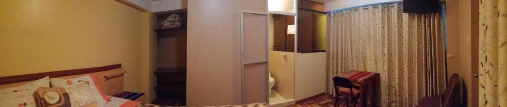 A hotel room with a bed, a wardrobe, a small table, and a curtain.